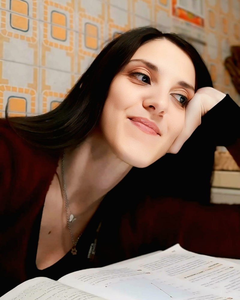 Portrait of Francesca Librandi, smiling, leaning on an open book